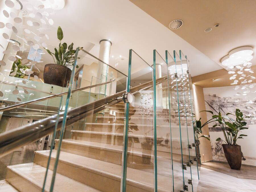 A modern staircase with glass railings and potted plants.