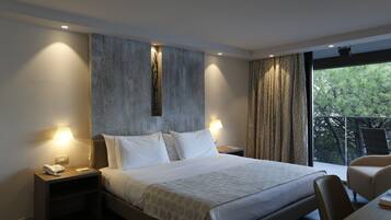 Una habitación de hotel moderna con una cama grande, dos mesitas de noche, un escritorio y vistas a árboles a través de la ventana.