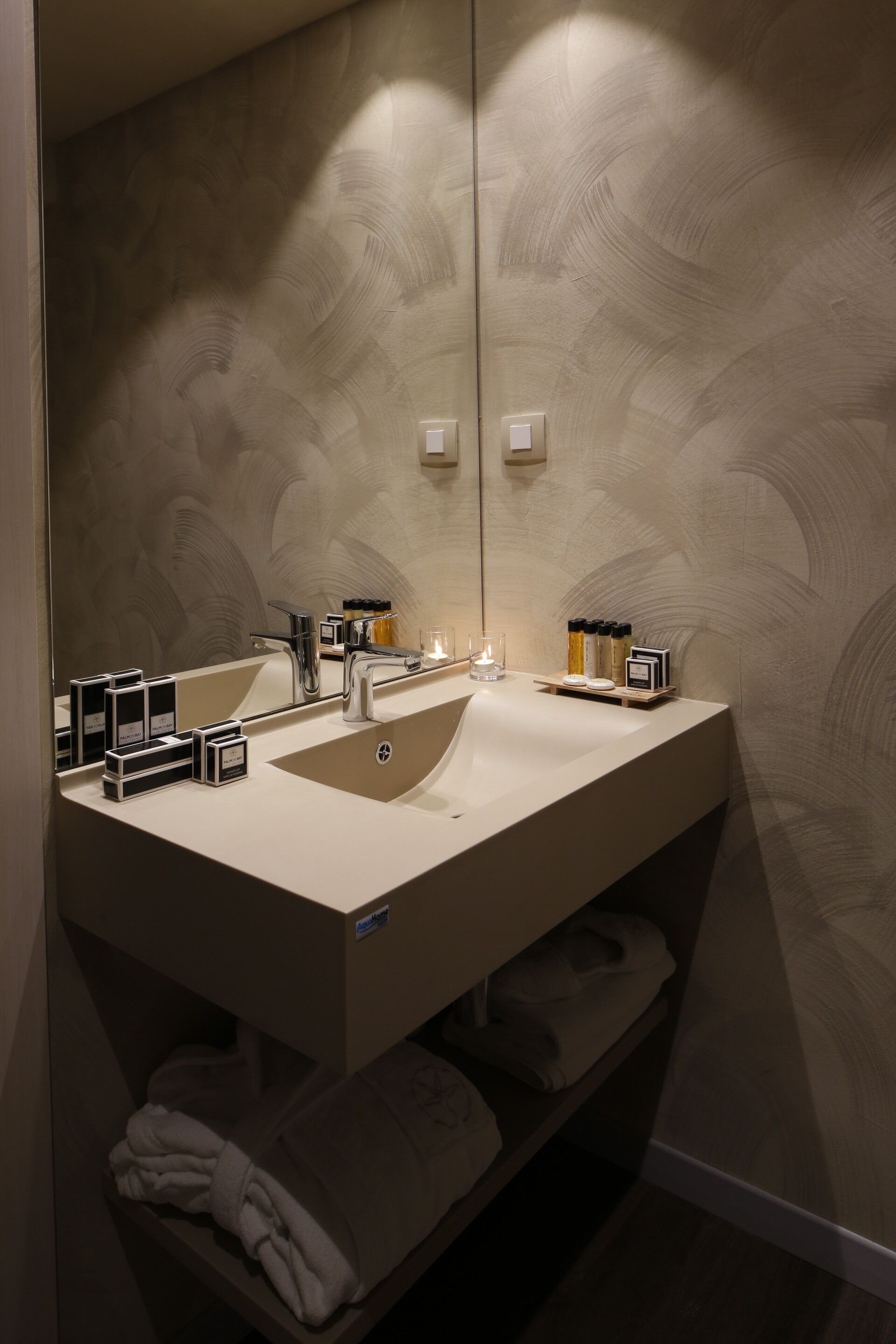 A modern bathroom with a large mirror, a sink, and a towel rack.