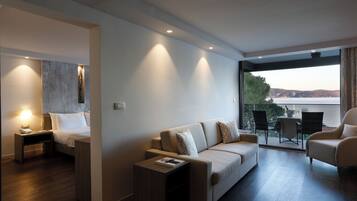 Una habitación de hotel moderna con una cama, un sofá, una mesita y un balcón con vistas al agua.