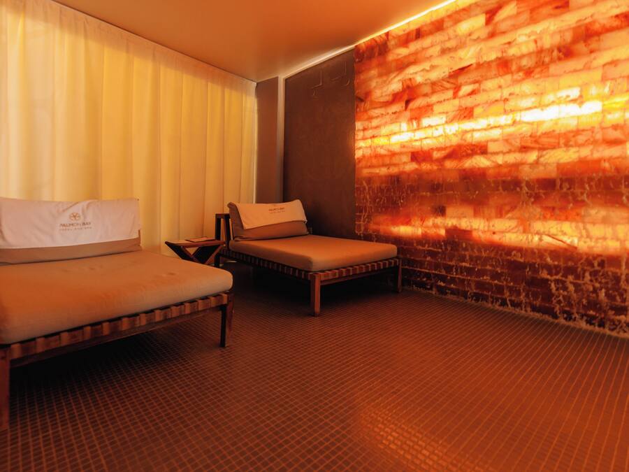 A hotel room with two beds, a brick wall, and a tiled floor.