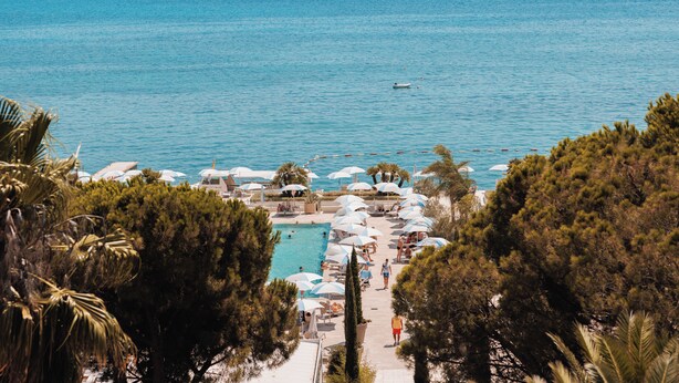 A poolside area with umbrellas and lounge chairs, overlooking a large body of water. - Palmon Bay Hotel & Spa (Igalo)