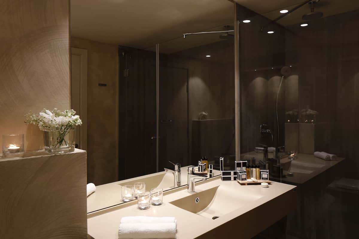 A modern bathroom with a large mirror, a beige vanity, and a glass-enclosed shower.