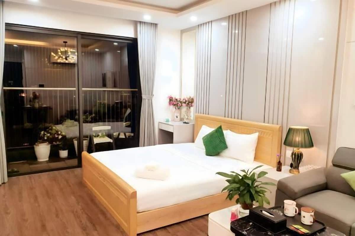 Een hotelkamer met een bed, nachtkastje, lamp en een glazen schuifdeur naar een balkon.