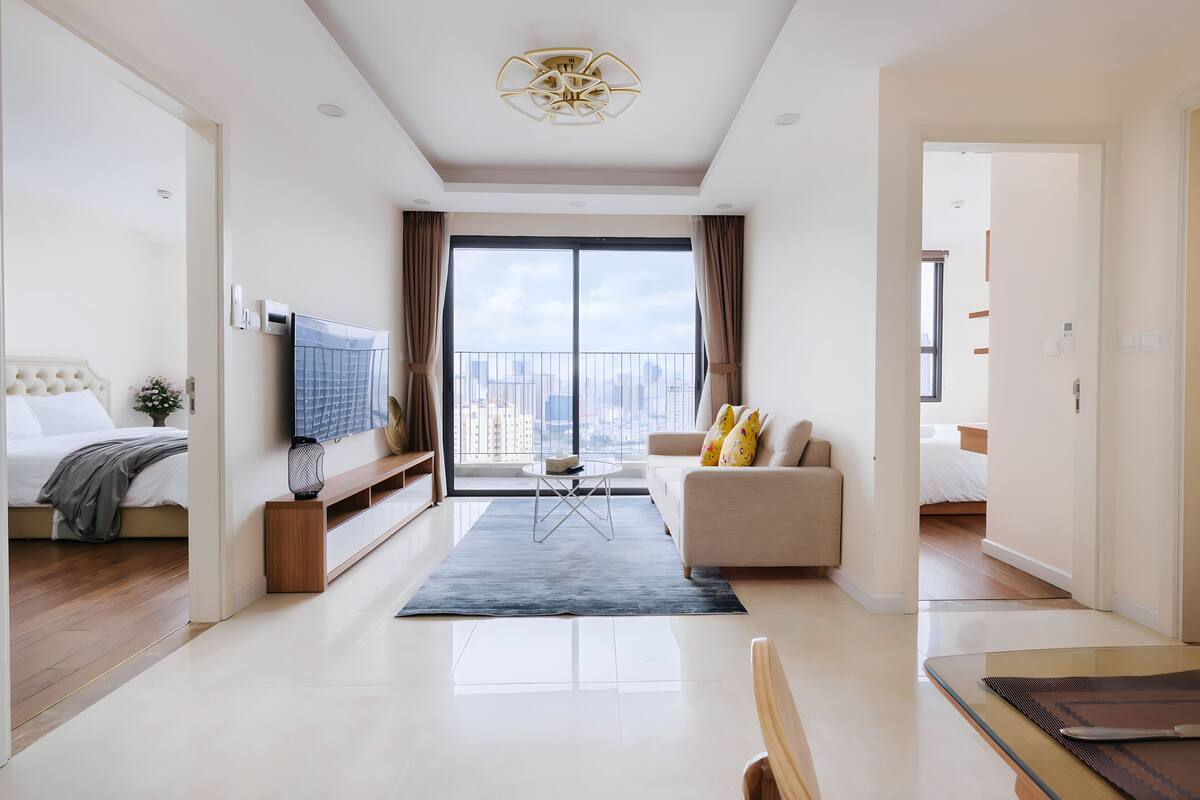 Een moderne hotelkamer met een groot balkon, een bank, een televisie en een eethoek.