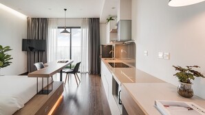 A modern hotel room with a kitchenette, a dining area, and a large window with curtains. - Mira Housing- Vinhomes D'Capitale  (Hanoi)