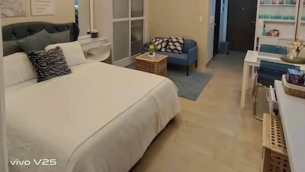 Un dormitorio moderno con una cama grande, un sofá azul, un escritorio y una araña.