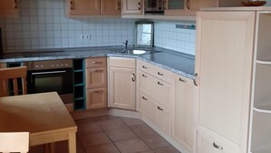 Eine Küche mit Holzausstattung, einer Mikrowelle, einem Spülbecken und einem Essbereich mit Tisch und Stuhl.