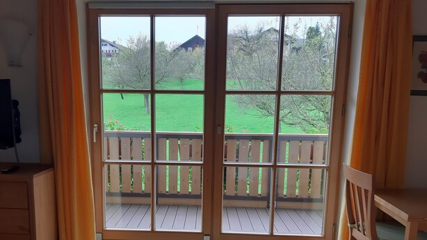 Ein Zimmer mit einer Schiebetür und einem Balkon mit Holzgeländer.