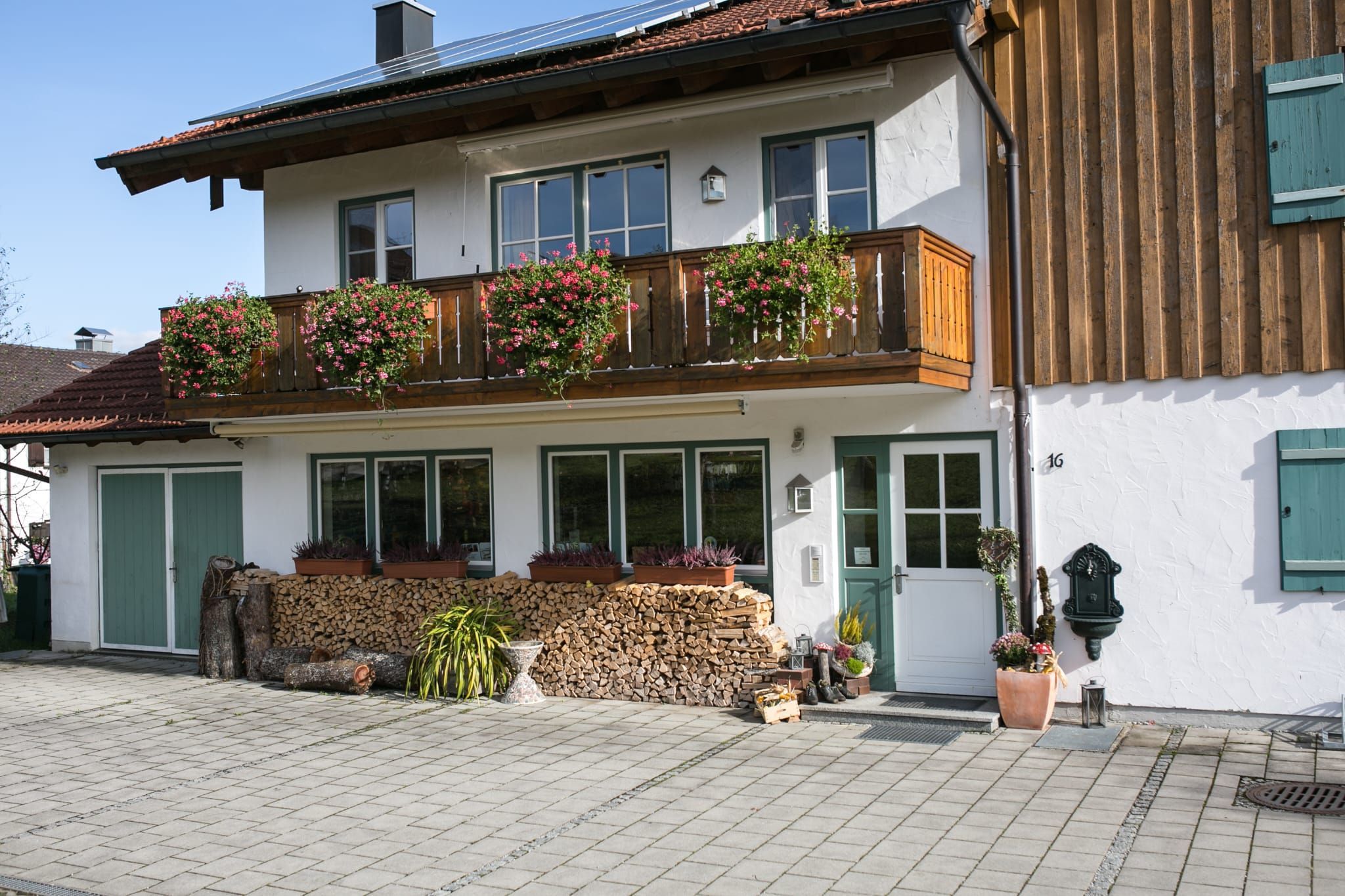 Un bâtiment à deux étages doté d’un balcon, d’une clôture en bois et de diverses plantes en pot.