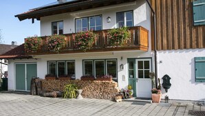 Ein zweistöckiges Gebäude mit einem Blumen geschmückten Balkon, einer Holztreppe und einer Tür mit der Nummer 16.