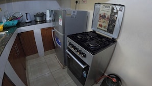 Een kleine keuken met een gasfornuis, een koelkast en een magnetron.