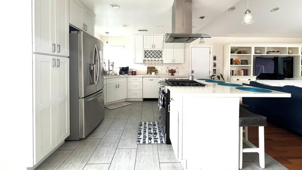 A modern kitchen with white cabinetry, stainless steel appliances, and a central island.