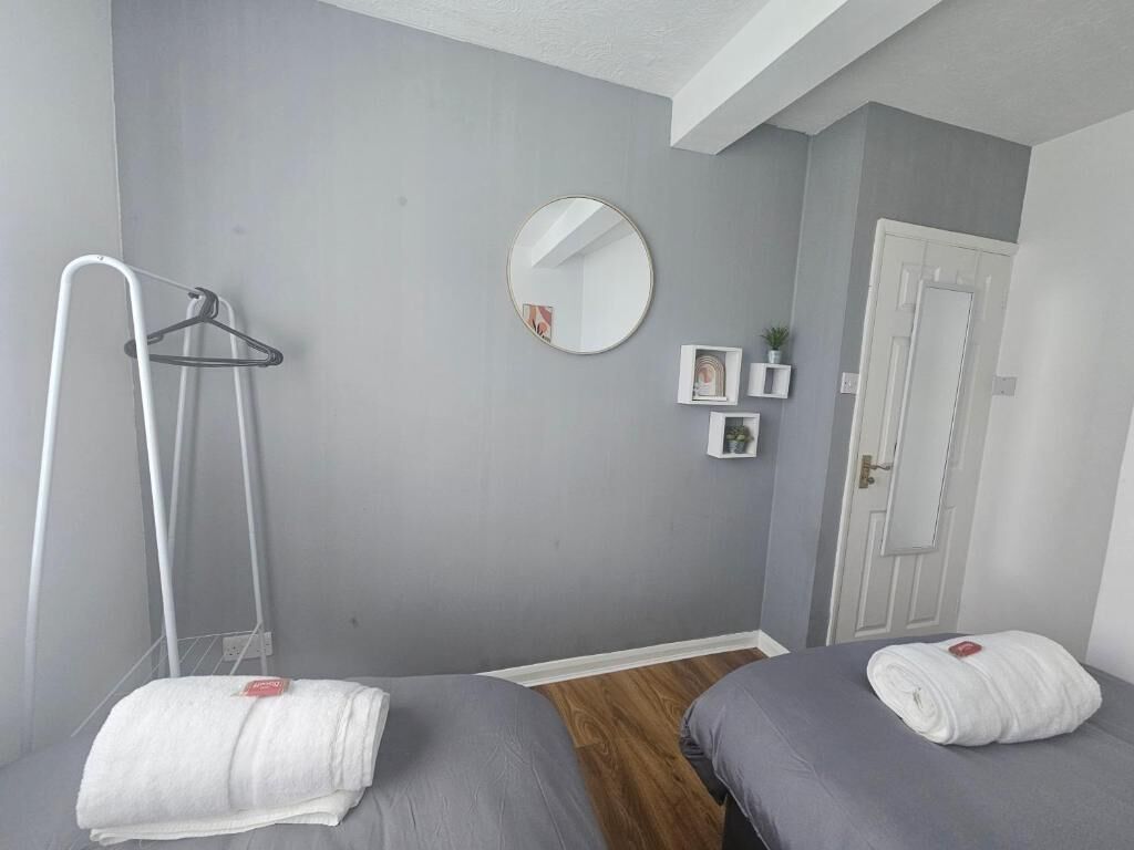 A room with two beds, a mirror, a towel rack, and a door.