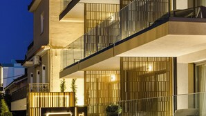Una entrada de hotel moderna con un llamativo letrero de 'G Boutique Hotel', una barandilla de cristal y un camino pavimentado que lleva a la entrada.
