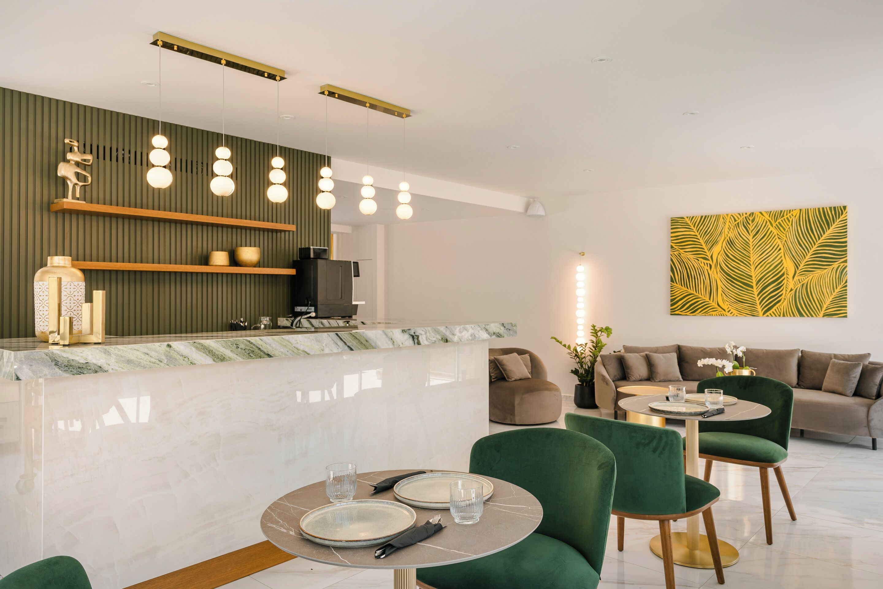 Una hall moderna di un hotel, con una scrivania della reception in marmo, sedute rivestite in verde e un elemento decorativo a parete.