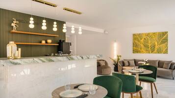 Una hall moderna di un hotel, con una scrivania della reception in marmo, sedute rivestite in verde e un elemento decorativo a parete.