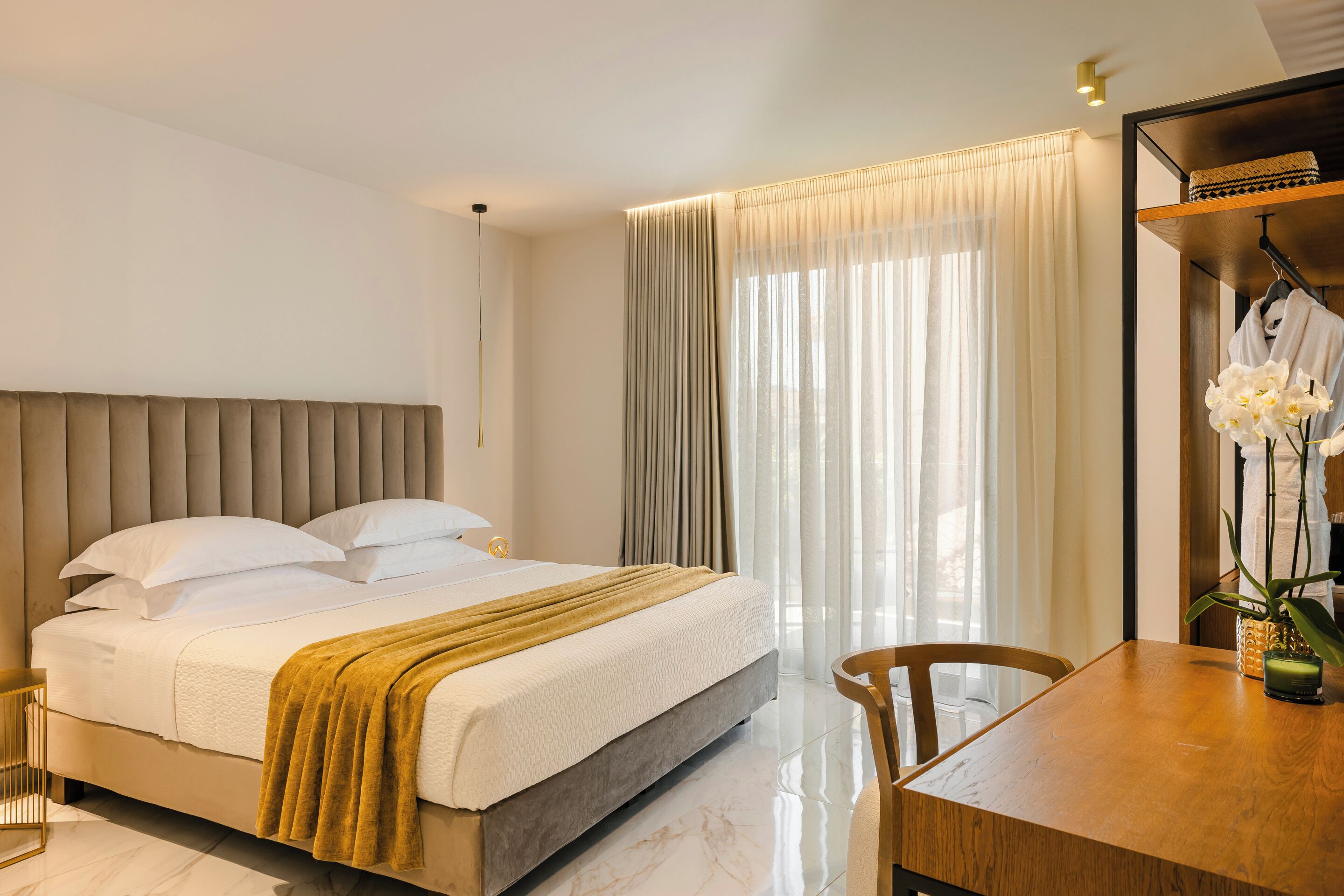 A modern hotel room with a large bed, a wooden dining table, and a small seating area.