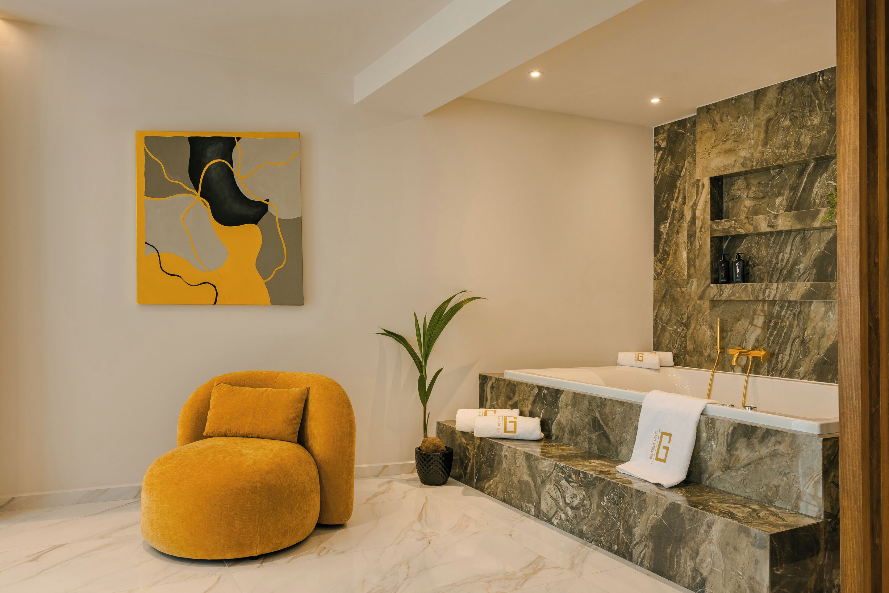 A modern bathroom with a marble sink, a yellow chair, a potted plant, and a wall art piece.