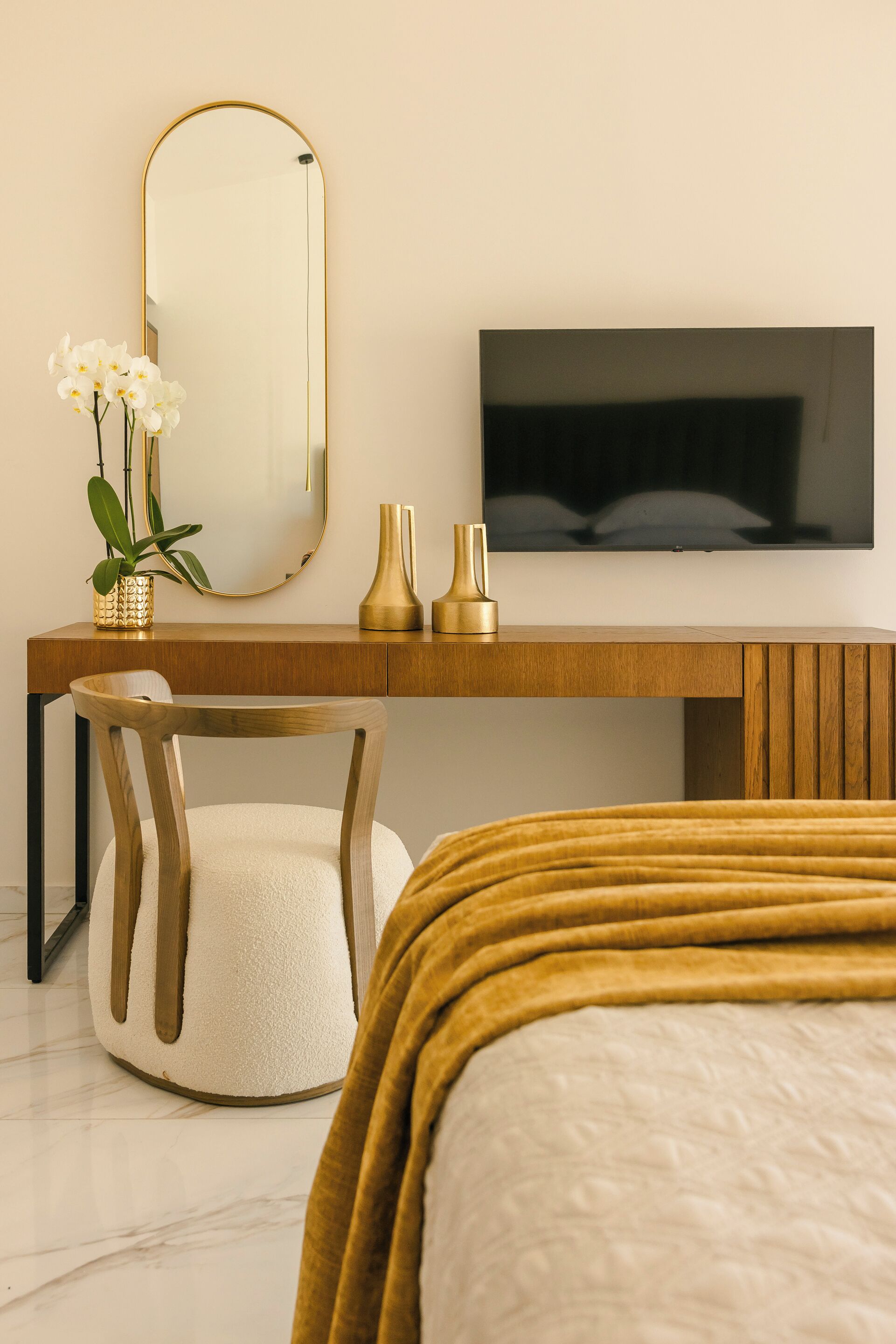 A modern bedroom with a wooden desk, a television, a chair, and a bed with a yellow blanket.
