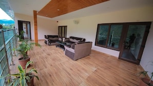 A spacious balcony with wooden flooring, a sofa set, and potted plants. - Amritara Social Palace (Chinyalisaur)