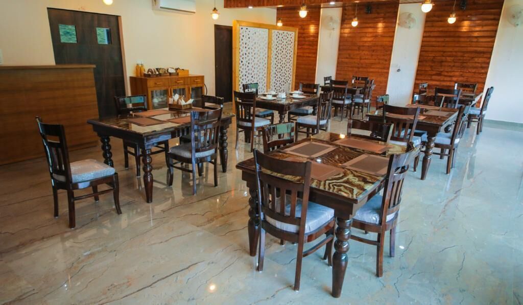 A spacious dining area with multiple wooden tables and chairs, a polished marble floor, and a wooden accent wall.
