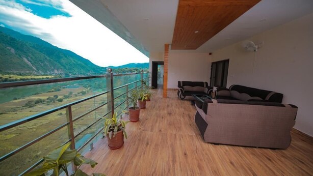 A balcony with a wooden floor, two sofas, and potted plants. - Amritara Social Palace (Chinyalisaur)