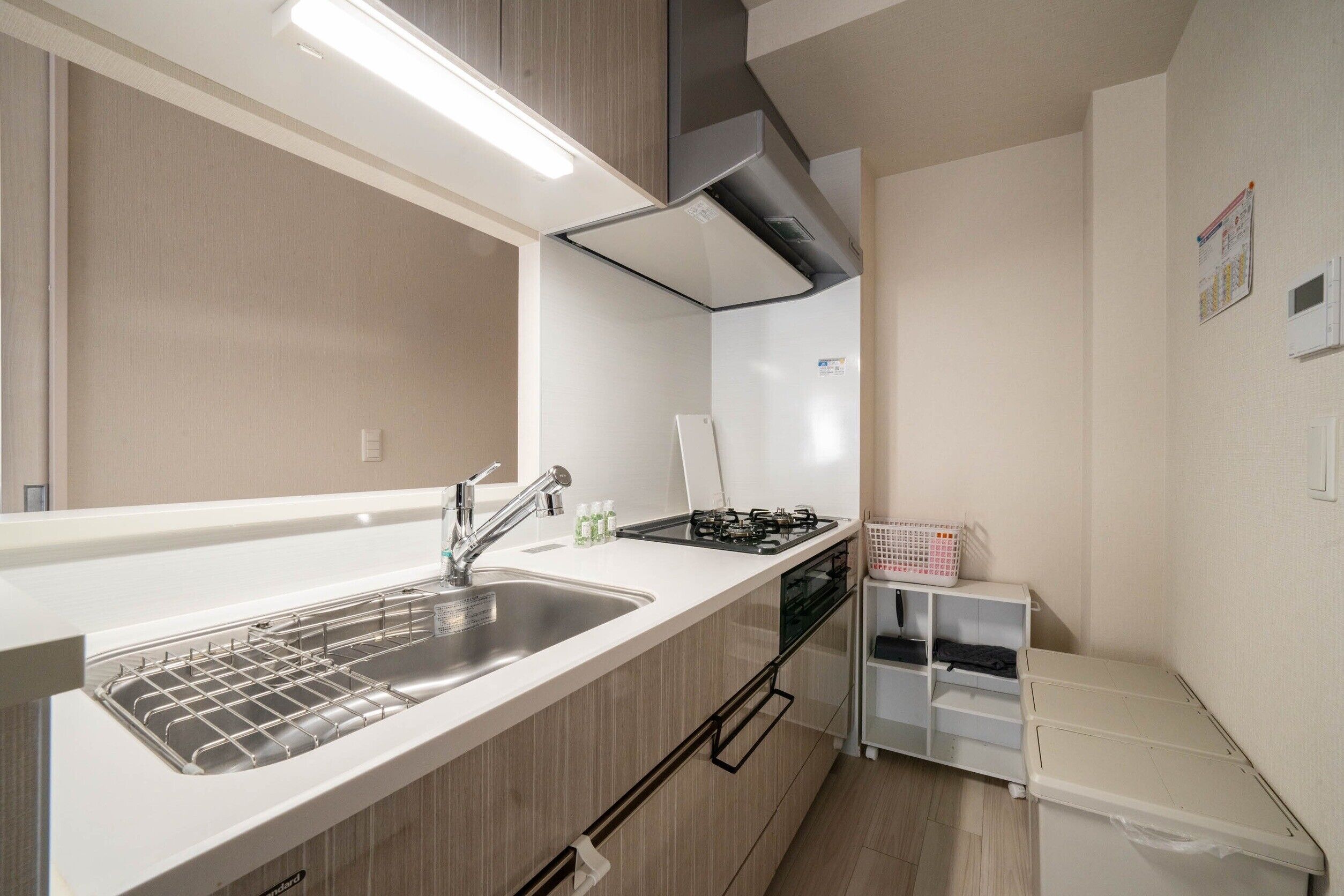 Cocina compacta con un lavamanos de acero inoxidable, cocina a gas y encimera blanca.