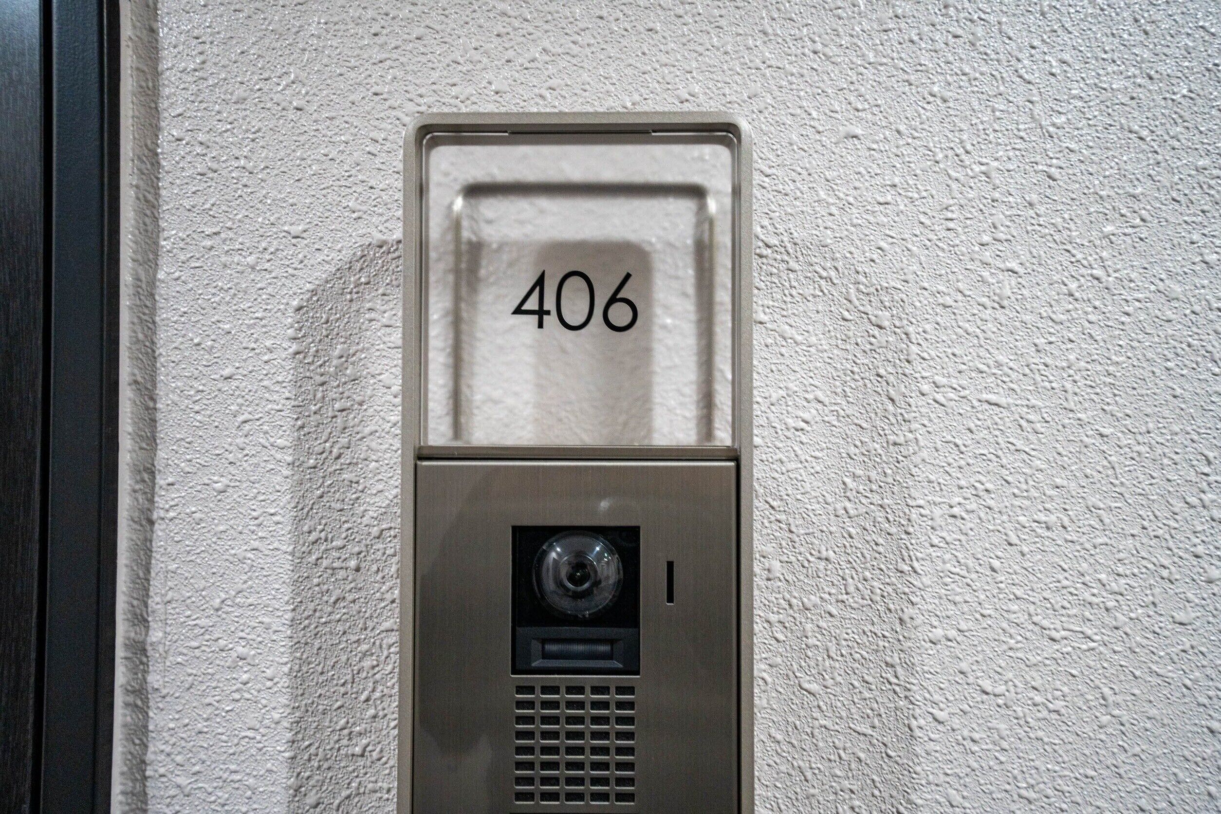 A wall-mounted intercom with the number 406.