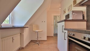 Una cucina moderna con forno integrato, forno a microonde e uno sgabello da bar.