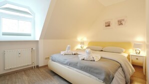 Una camera da letto con un letto, lampade sui comodini, un termosifone e una finestra.