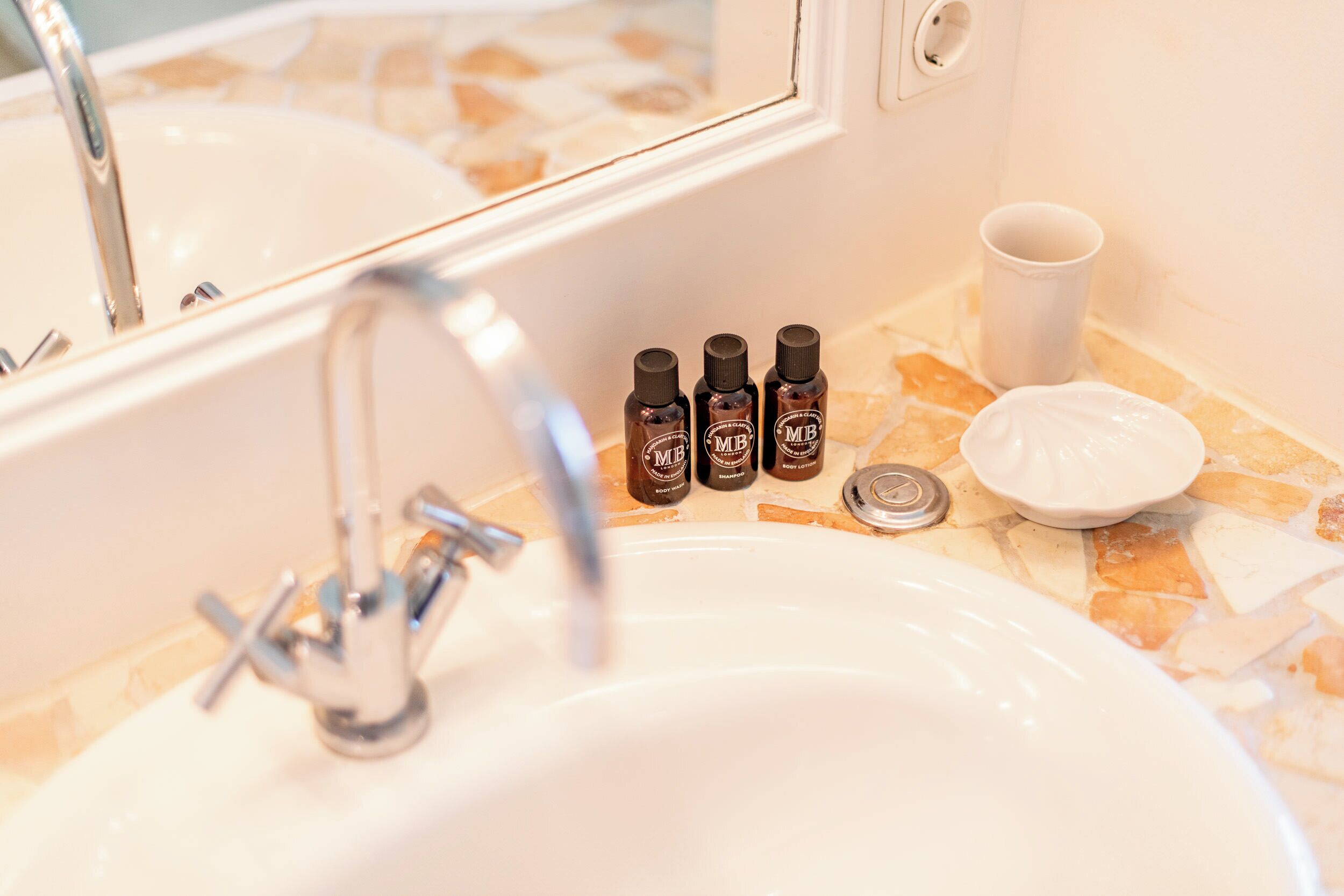 Un lavabo de salle de bain avec trois flacons d’huiles essentielles, une tasse et un porte-savon.