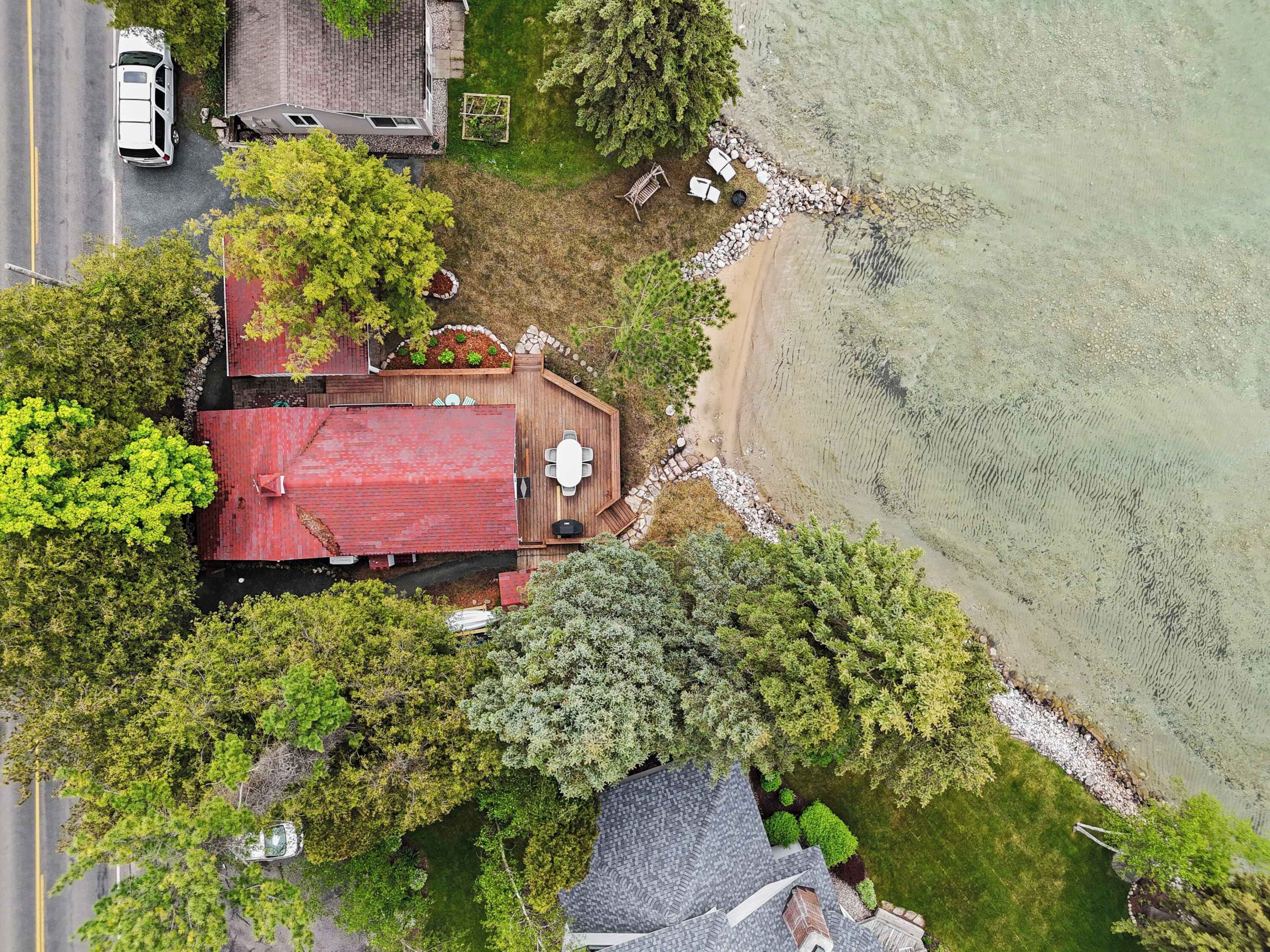 A house with a red roof, a deck, and a beach view.