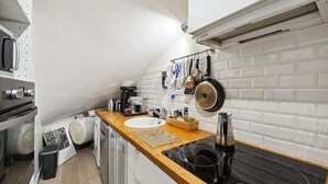 Een moderne keuken met een houten aanrecht, een witte spoelbak en een zwart fornuis.