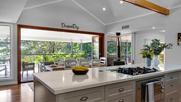 Una cocina moderna con una isla grande, armarios blancos y vistas a un patio exterior.