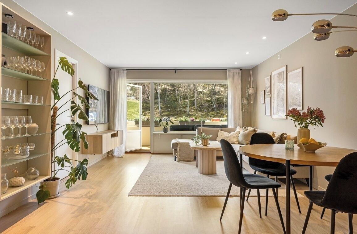 A modern living room with a dining area, large windows, and a view of the outdoors.
