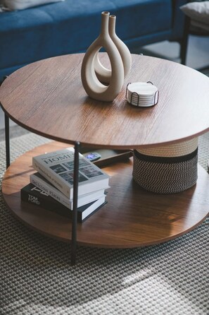 A round wooden coffee table with a woven basket underneath, a stack of books, and a vase on top. - Central, bright, cozy, and elegant Benci apartment (Ciudad de México)