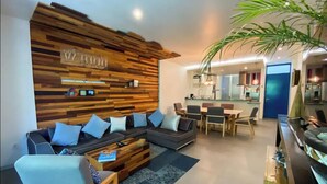 Un salon moderne avec un mur d’accent en bois, un ensemble de canapés, une table basse et un coin repas.