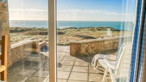 Une terrasse avec vue sur la mer, des murs en pierre et un banc.