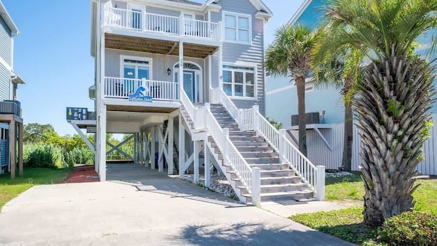 A two-story beachfront house with a balcony and a staircase leading to the upper level. - The Saltwater Shack: Early Bird Special! (Oak Island)
