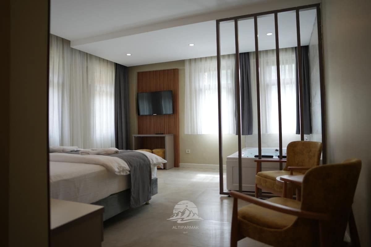 A hotel room with a bed, a desk, a chair, a TV, and a large window with curtains.