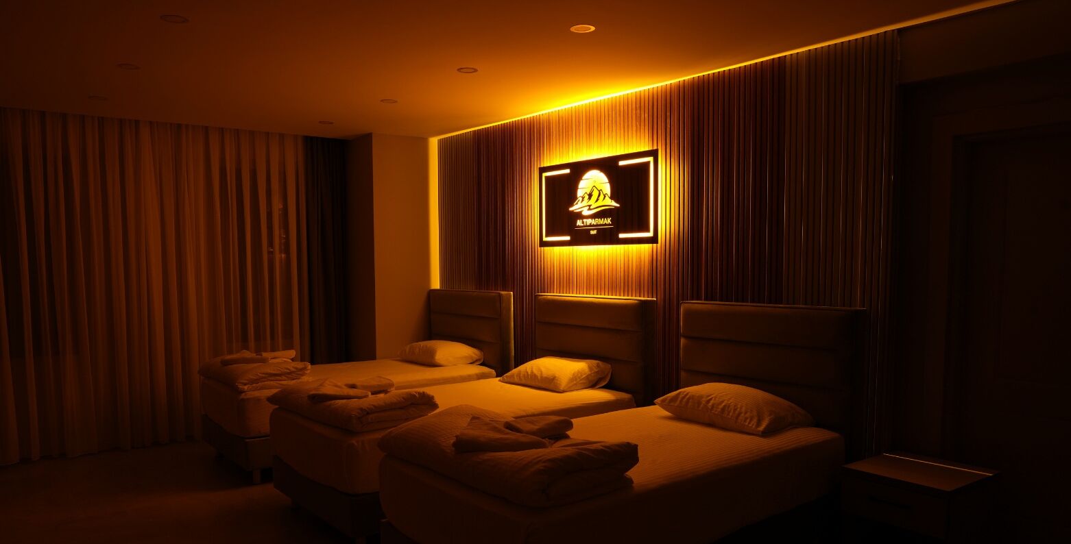 A hotel room with two beds, a TV mounted on the wall, and a curtain on the left.