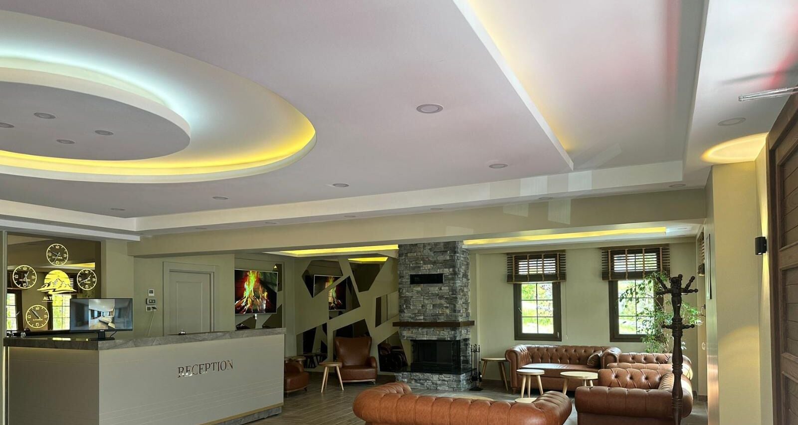 A modern reception area with a reception desk, seating area with leather sofas, a stone fireplace, and a staircase leading to another level.