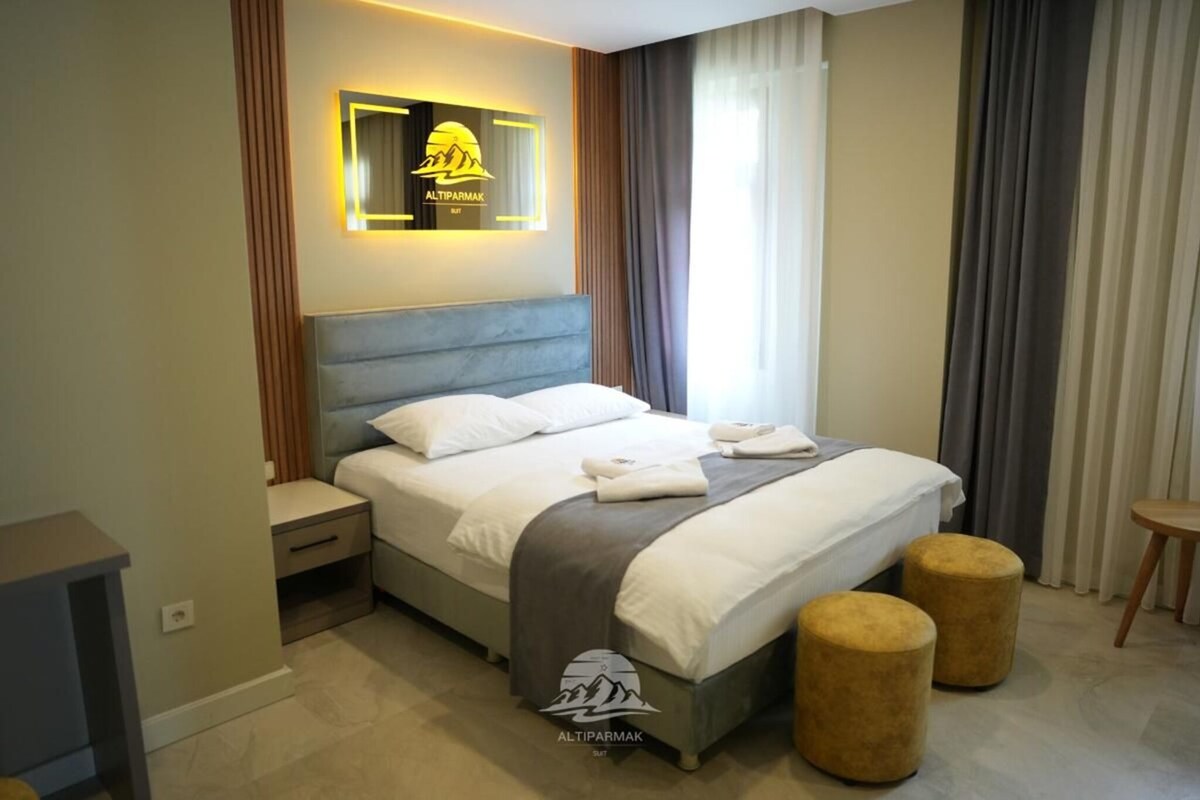 A modern hotel room with a bed, bedside tables, and a wall-mounted light fixture.