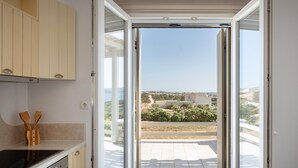 Una puerta corredera abierta a un balcón con una vista despejada del paisaje circundante.