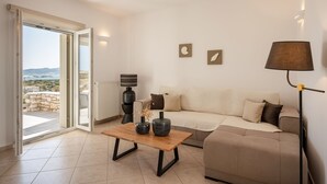 Una sala de estar moderna con un sofá, una mesa de centro y una lámpara. Se ve el exterior a través de un ventanal corredero.