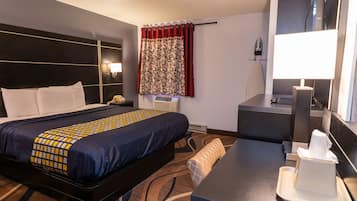 A hotel room with a bed, bedside table, lamp, and a mirror.