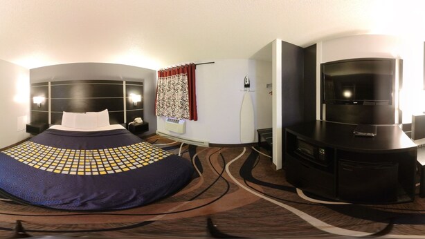 Ein Hotelzimmer mit Bett, Sitzgelegenheit, Fernseher und Minibar.