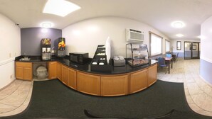 Una cocina limpia y moderna con una encimera curva, cafeteras y un refrigerador.