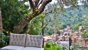 A cushioned outdoor sofa with a view of a hillside town.